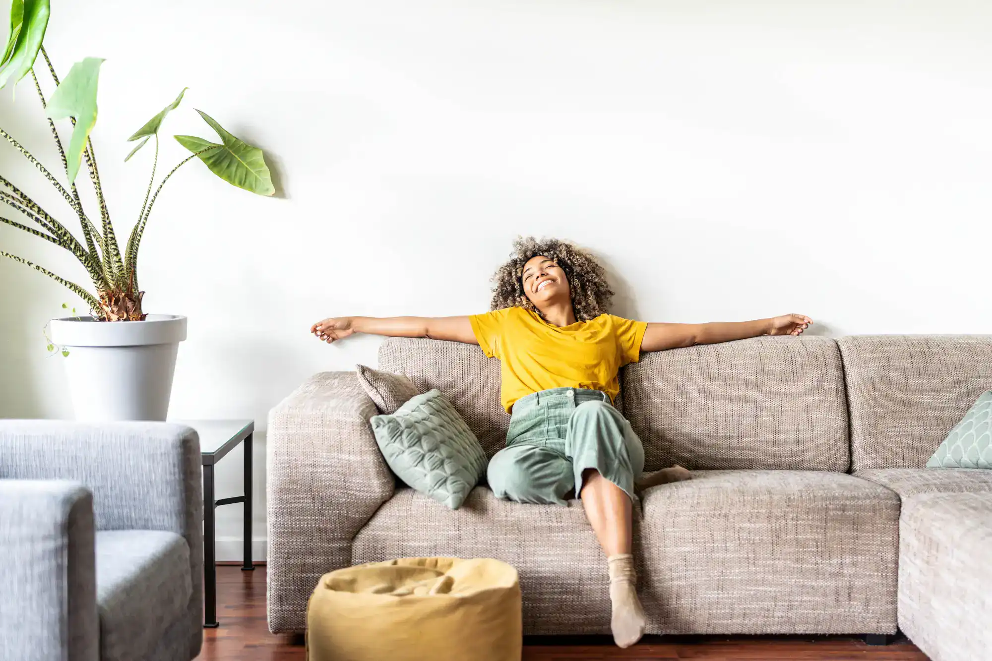 Person smiling on a sofa inside her SkyMor Sugar Hill home for rent in Gwinnett County.